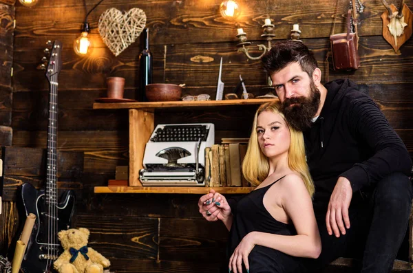 Couple spend romantic evening in gamekeepers house, wooden interior background. Romantic concept. Girl and man on calm faces relax in warm atmosphere. Couple in love hugs, cuddling together