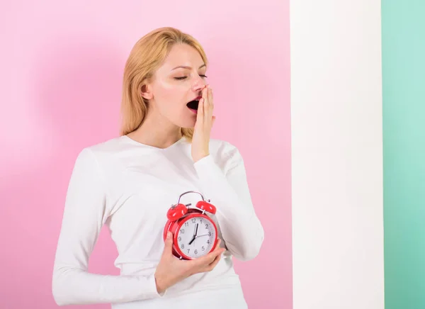 Oversleeping side effects is too much sleep harmful. Girl yawning face just woke up holds alarm clock pink background. Bad sleep habits and effects on your life. Lack of sleep bad for your health