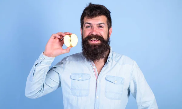 Homme barbu souriant tient fond bleu pomme. Soins de santé alimentation vitamine nutrition. La moitié des pommes mode de vie sain. Hipster démontre pomme écologique naturelle. Concept de valeur nutritive — Photo