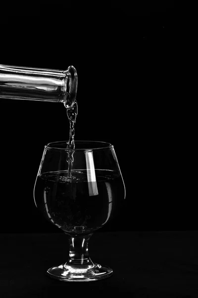 Bebidas e álcool conceito. Uísque derramado em vidro baixo no fundo preto . — Fotografia de Stock