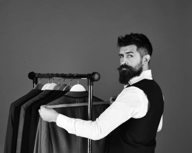 Elbise rafında sakallı bir adam. Tasarımcı önlem alır