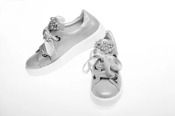 Glamorous sneakers concept. Schoenen voor meisjes en vrouwen versierd met parel kralen. Leuke schoenen geïsoleerd op een witte achtergrond. Paar bleke roze vrouwelijke sneakers met fluweel linten — Stockfoto