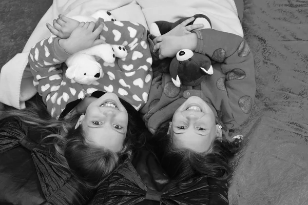 Pijamalı çocuklar kırmızı arka planda oyuncak ayılara sarılıyorlar. — Stok fotoğraf