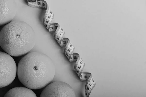 Concepto de atletismo y pérdida de peso. Naranjas cerca de cinta métrica retorcida — Foto de Stock