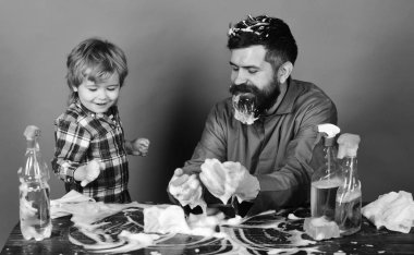 Baba ve oğlu yeşil arka planda temizlik malzemeleri.