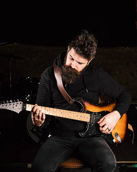 Férfi elfoglalt arc fekete ruhában tartja gitár, játszani — Stock Fotó