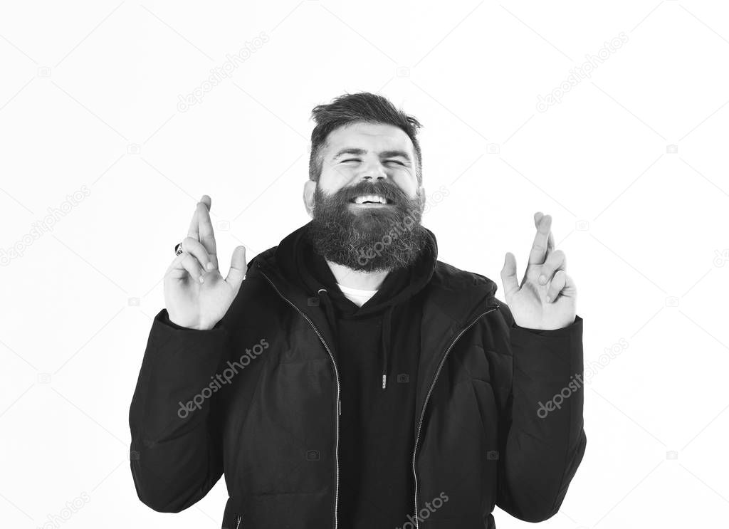 Man with beard and closed eyes crosses fingers, gesture