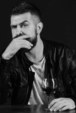 Sakallı bir adam kahverengi arka planda şarap kadehi tutuyor..