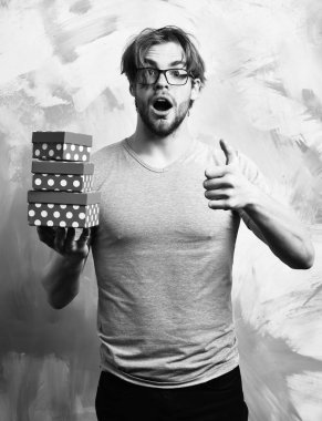 Beyaz sakallı seksi maço adam elinde hediye kutuları tutuyor.