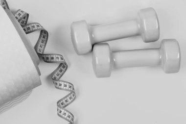 Barbell bükülmüş şerit metre ve mor yoga mat yanında. Dambıl ve ölçü birimi teyp siyan mavi renkli