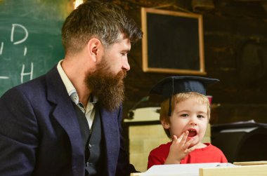Evde eğitim kavramı. Hevesli çocuk öğretmen ile eğitim. Ödev, çocuk, yardımcı olur kontrol baba evlat. Öğretmen formal giyim ve öğrenci sınıfta kolej, kara tahta arka plan