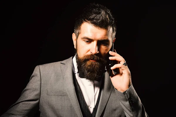 Man with long beard holds mobile phone. Business and phone talk concept. Macho in formal suit