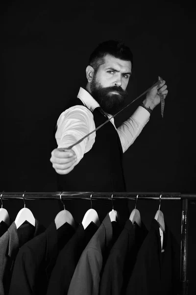 服のラックでのベストのひげを持つ男。ハンガー近くのデザイナーの作品。近代的なワードローブの選択 — ストック写真