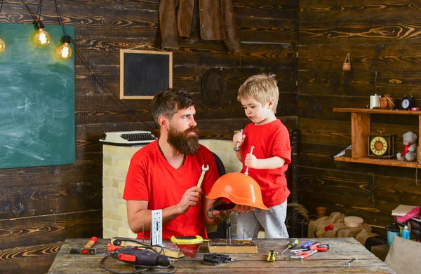 Baba, anne-baba sakal ile oğlu Emanet okul atölye öğretim kask tutar. Evlat, çocuk neşeli cıvata veya vida, baba ile handcrafting sırasında eğlenmek tutar. Güvenlik ve koruma kavramı