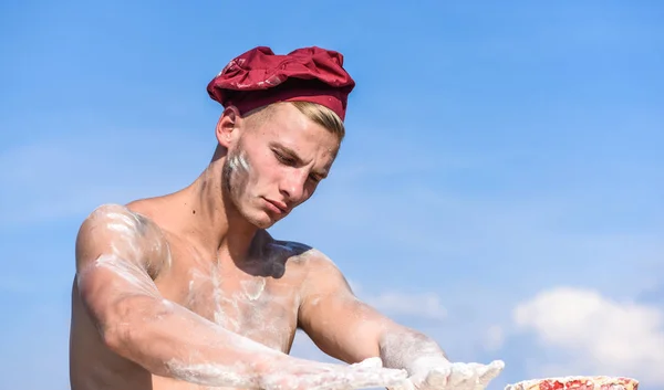 Chef en chapeau blanc sur le visage strict, ciel sur le fond. Homme avec le torse musculaire recouvert de farine semble attrayant. Homme avec l'aspect attrayant fonctionne comme boulanger, espace de copie. Concept de chef sexy — Photo