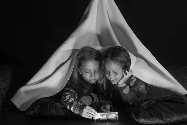 儿童和睡衣党的概念。有兴趣面孔的女孩躺在黑色背景的毯子下 — 图库照片