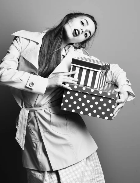 Maquillage de mode et robe vintage beige tenant des boîtes cadeaux colorées sur fond de studio bleu, fille colorée sérieuse avec cheville — Photo