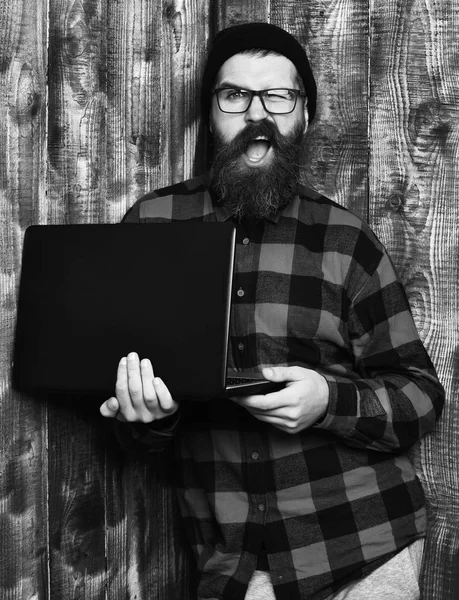 Lunettes sur fond brun studio vintage en bois, barbu brutal hipster caucasien tenant ordinateur portable — Photo
