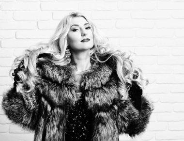 Gri kürklü ve siyah kadife eldivenli güzel, uzun kıvırcık sarı saçlı, seksi, zengin bir kadın.