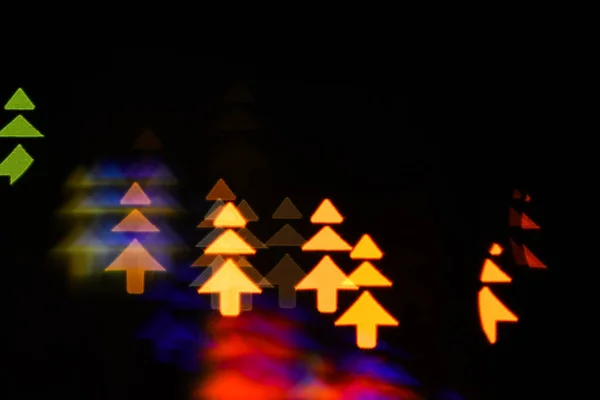 Lichten van Kerstmis garland wazig op zwarte achtergrond. Lichten van kleurrijke garland als prachtige achtergrond wazig. Vakantie Kerstdecoratie met silhouet van kerstbomen. Kerst concept — Stockfoto