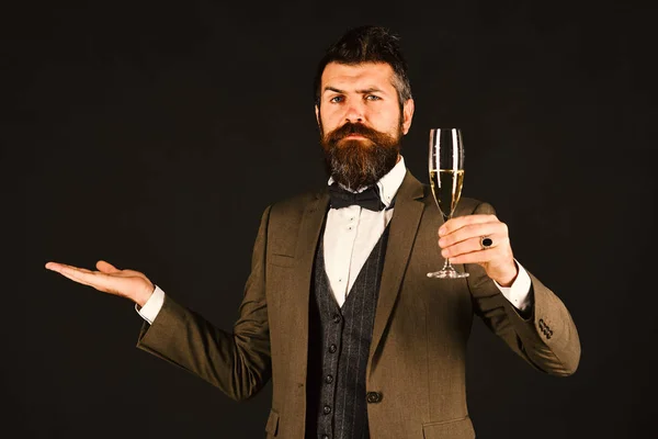 Macho in retro suit cheers with alcoholic drink on brown background. Birthday party concept. Businessman with serious face