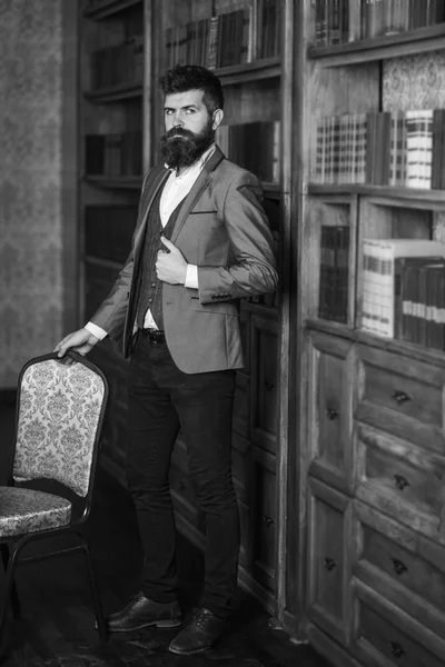 Elegant man in a suit stands in vintage room. Fashion