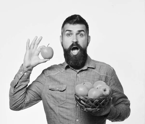 Concepto de jardinería y cultivos de otoño. Agricultor con la cara sorprendida sostiene manzana roja . —  Fotos de Stock