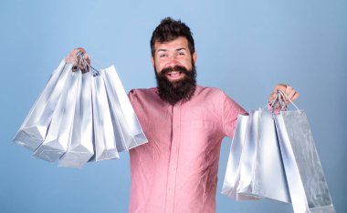 Satış sezon indirimlerle alışveriş adam. Satış ve indirim kavramı. Sakal ve bıyık tutun alışveriş torbaları, açık mavi renkli olan adam. Mutlu yüz hipster bağımlısı alışveriş veya Alışverişkoliğin