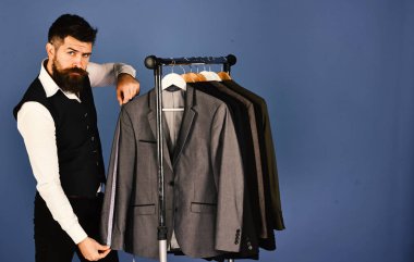 Modern dolap kavramı. Terzi emin yüz ile özel ceketler yakınındaki ölçüm bandı tutar