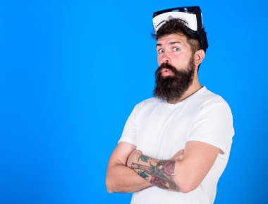 Sakal ve bıyık Vr gözlük, mavi arka plan ile olan adam. Adam Vr gözlük veya baş ile ekran monte. Hipster sürpriz yüzündeki göğsüne, kopya alanı geçti ellerini tutar. VR teknolojisi kavramı
