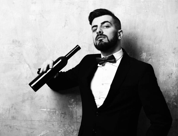 старый потрескавшийся бежевый фон. Концепция вечеринки время и ночь после работы. Бородатый босс с любопытным выражением лица держит бутылку вина
