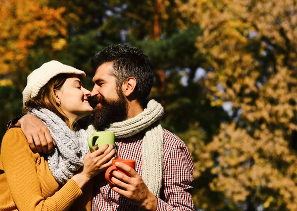 Coppia innamorata al parco tiene tazze di tè o caffè. Relazione e concetto di bevanda calda. Ragazza e barbuto ragazzo — Foto Stock