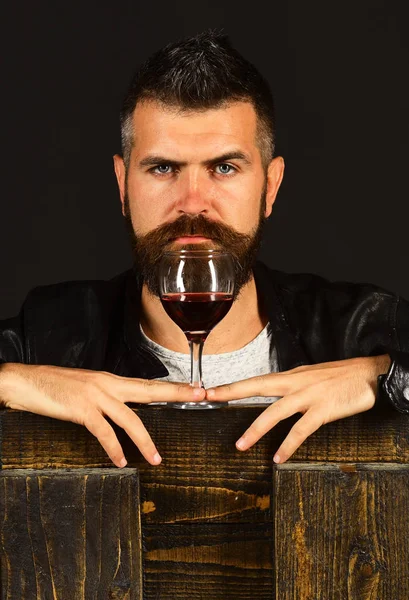 ソムリエは、高価な飲み物を味します。ひげを持つ男は、茶色の背景にワインのガラスを保持しています。 — ストック写真