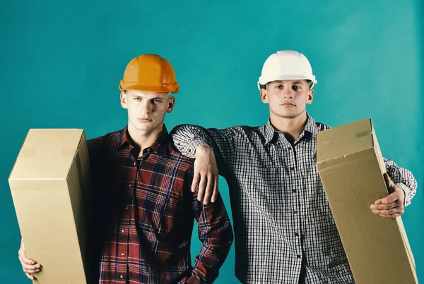 Concepto de entrega y embalaje. Los hombres con caras seguras sostienen cajas de cartón aisladas en verde —  Fotos de Stock