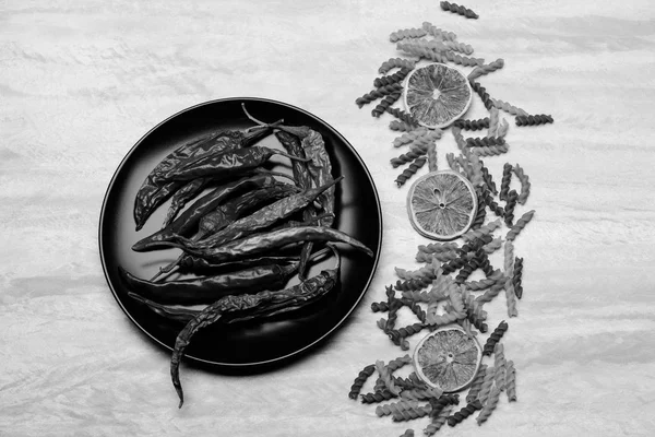 Poivron rouge sur plaque céramique noire avec pâtes et ingrédients — Photo