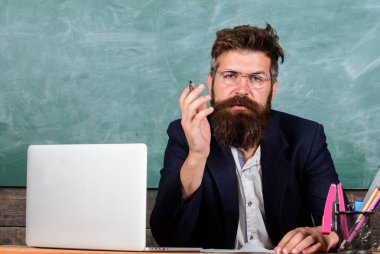 Eğitimci bitmiş bir açıklama sormak şey temiz. Kim soruyu cevaplamak için hazır. Okul öğretmeni hazırlamak soru sormak. Öğretmen hipster gözlük sit sınıf kara tahta arka plan ile sakallı