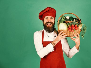 Cook mutlu yüz içinde burgundy üniforma ile sebze sepet içinde tutar. Yeşil bakkal kavramı. Lahana, turp ve brokoli Şef tutar