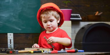 Çocukluk kavramı. Çocuk Oluşturucusu'nu veya repairer oynamak, aletlerle çalışırız. Turuncu baret veya kask, çalışma odası arka plan çocuk evlat. Gelecekteki kariyer mimarisi veya bina hakkında rüya çocuk