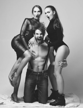 Çıplak kaslı bir adam ve iki seksi kız arkadaşı var..