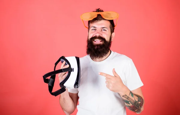 Man bearded hipster with virtual reality headset and louvered sunglasses red background. Alternative reality. Which glasses choose louvered or virtual. Man making decision what choose real or virtual
