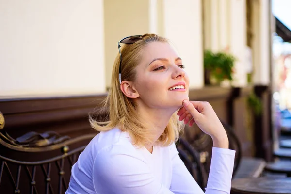 Pleasure on her mind. Woman blonde dreamy smiling face outdoors, building background defocused. What do girls dream about. Lady happy dreaming while relaxing cafe terrace. Pleasant thoughts