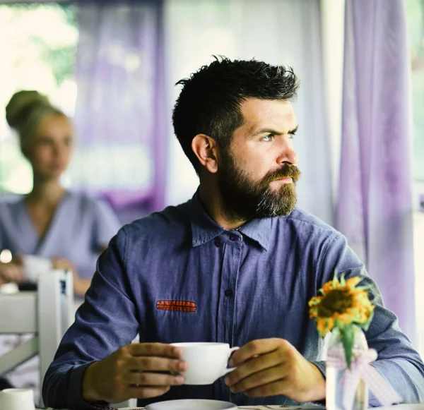 Man with beard holds cup of hot drink