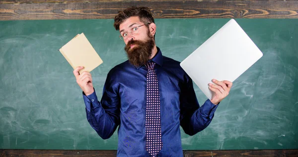 Fique moderno com a tecnologia. Professor hipster barbudo detém livro e laptop. As tecnologias modernas beneficiam. Digital contra papel. Escolha o método correto de ensino. Professor escolhendo abordagem de ensino moderno — Fotografia de Stock