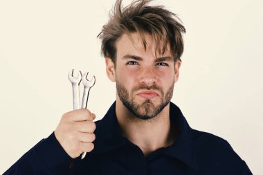 Katı yüzlü bir adam İngiliz anahtarlarını beyaz arka planda tutar.