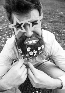 Hipster neşeli yüzündeki sakallı yıldız ile poz gözlük ve dudak şeklinde. Adam güzel sakal daisy çiçeklerle benziyor. Photosession kavramı. Sakal ve bıyık, yeşil renkli olan adam