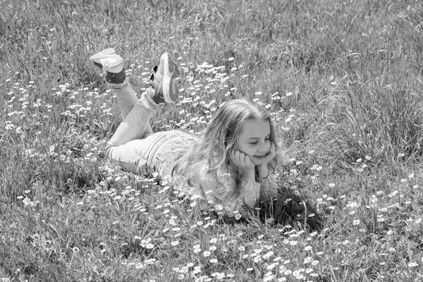 Ruhe und Frieden Konzept. Mädchen mit ruhigem Gesicht verbringen ihre Freizeit im Freien. Kinder genießen frühlingshaftes sonniges Wetter auf der Wiese. Mädchen liegt auf Gras auf Grasfläche, grüner Hintergrund — Stockfoto