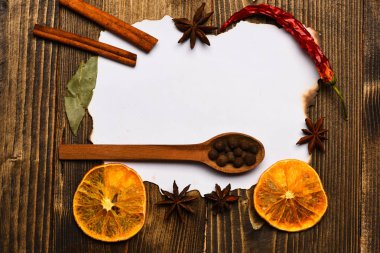 Baharatlar, beyaz kağıt mutfak otlar yatıyordu. Mutfak tarifi kavramı. Ahşap arka plan üzerinde kağıt parçası. Tarçın, kurutulmuş portakal ve anasonu lay için tarifi, boş kağıt çevresinde alanı Kopyala