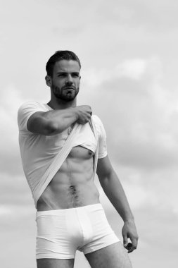 Beyaz tshirt ve iç çamaşırı giyen maço abs gösterir