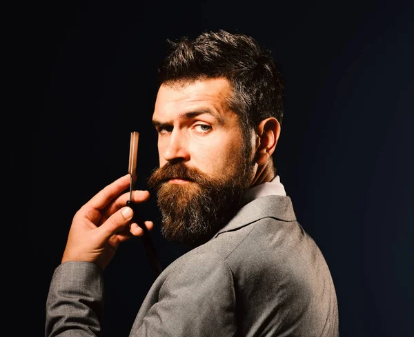 Man with long beard holds blade for razor. Barbershop advertising