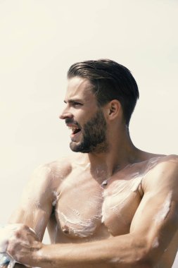 Açık gökyüzü arka plan üzerinde gülümseyen kıl olan adam. Adam seksi güçlü gövde ile köpük ile kaplı